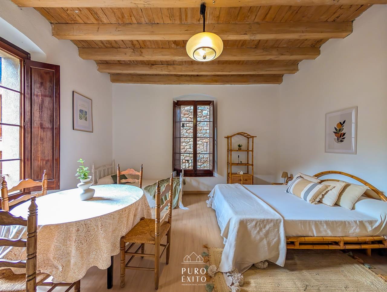 The same large bedroom from the other side, showing the deep stone-framed window and shutters.