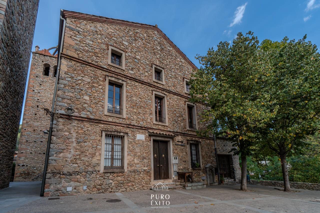 Casa Osor: a three-storey stone house on a small square in Osor, with the church bell tower rising behind it.