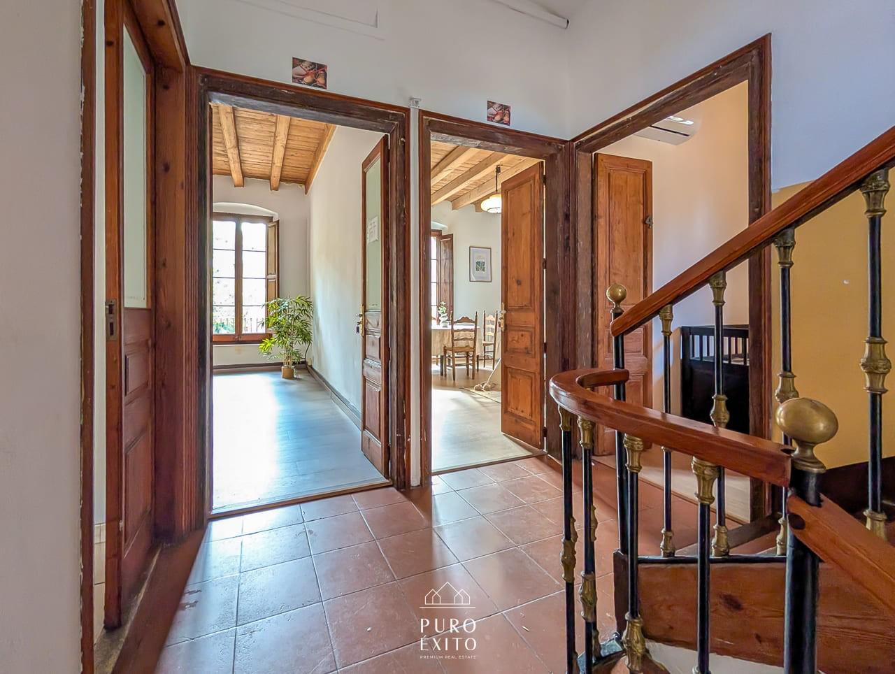 A landing with terracotta tiles and tall wooden doors standing open onto two rooms.
