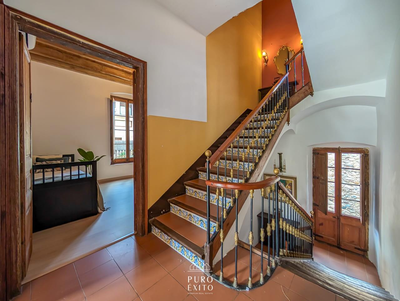The main staircase, with painted tile risers, a turned handrail and brass-topped balusters.
